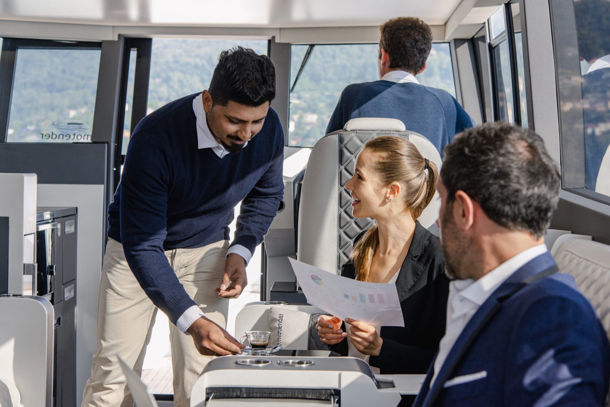 A business meeting on the best luxury boat in lake como limotender by moveolux - the waiter of the private boat brings coffee during meeting to a lady attending it