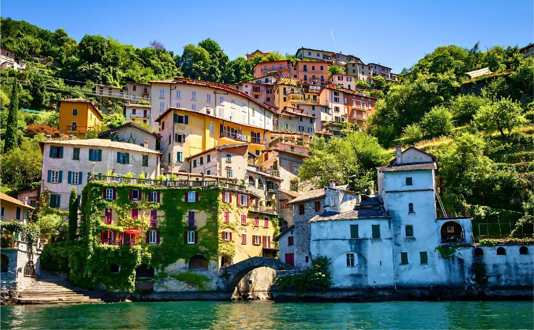 Borgo di Nesso sul Lago di Como con case storiche colorate e ponte medievale.