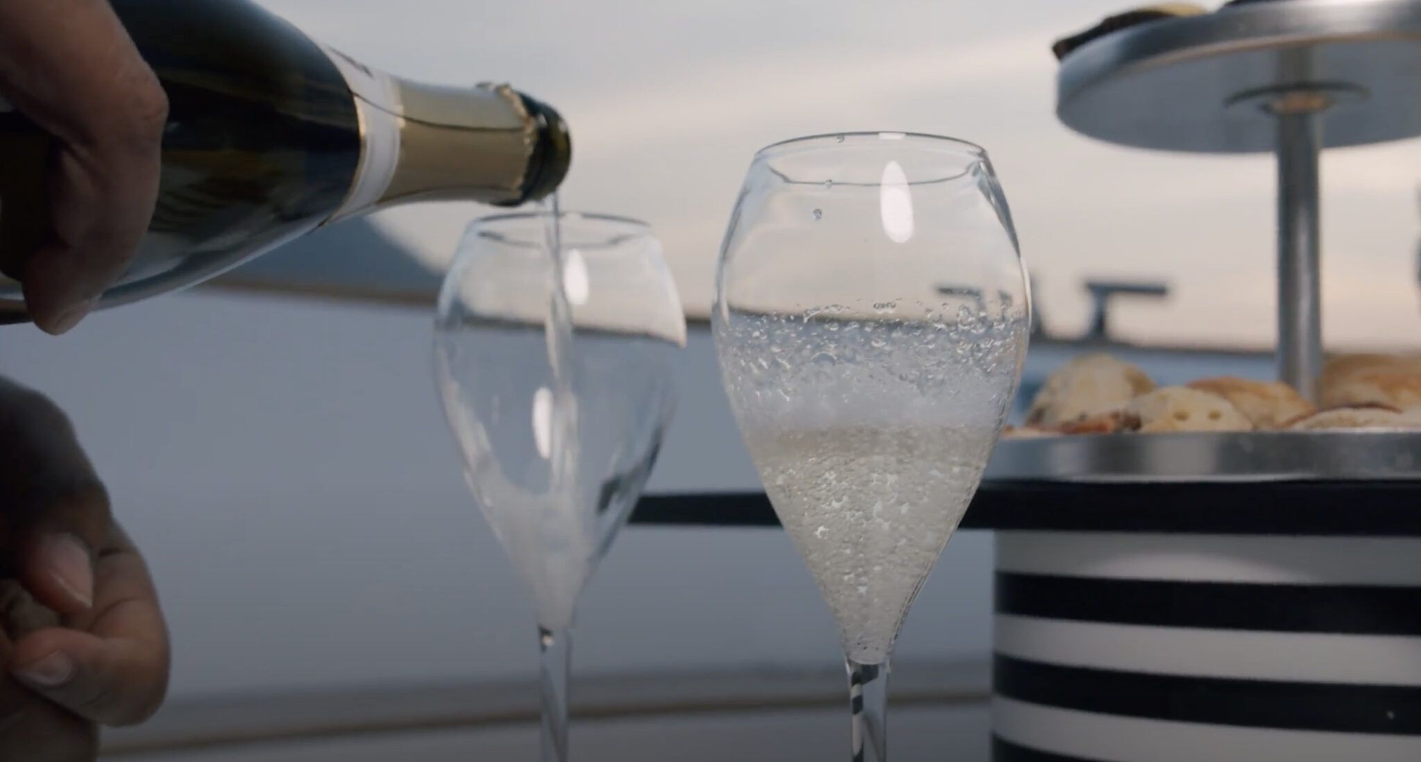 Close-up of champagne being poured into elegant glasses aboard a luxury boat on Lake Como.